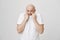 Portrait of upbeat positive bald caucasian male pulling t-shirt on face as if wanting to hide from camera, smiling and