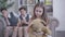 Portrait of upset caucasian little girl holding teddy bear as blurred twin brothers laughing at the background. Sad cute