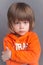 Portrait of an upset cute little boy in orange hoodie