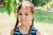 Portrait of an upset cute little girl with pigtails standing and looking at camera in summer