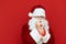 Portrait of upset Santa Claus on red background, warming from cold. Santa froze and looks into the camera with a sad face.