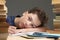 Portrait of upset schoolboy looking at textbook with homework