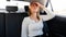 Portrait of upset young woman holding hand on her forehead because of the headache while riding in taxi car