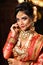 Portrait of very beautiful young Indian bride in luxurious bridal costume with makeup and heavy jewellery in studio lighting