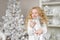 Portrait of very glad little girl with a gift box at hands in a light new year decoration studio