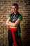 portrait of a very muscular Caucasian male model dancer in national costume against a brick wall