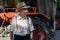 Portrait of very old farmer with straw hat explaining life in front of a red tractor