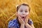 Portrait of a very surprised cute little girl in a field of wheat in the open air. Nature in the village