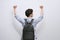 Portrait of victorious man looking up while standing on white background and celebrating with fists in the air