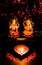 Portrait view of Ganesha and Luxmi idols with a terracotta lamp in the foreground and red bokeh in the background for Diwali