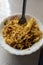 Portrait view of noodles with spoon in white bowl. Spicy asian instant noodles with pasta