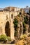 Portrait view of Ronda and its spectacular deep gorge, with a massive stone bridge and arches, Spain