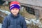 Portrait of a village boy on the background of a cattle stall. A child on the background of a winter cowshed