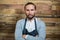 Portrait of waiter standing with arms crossed against wooden wall