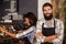 Portrait of waiter standing with arms crossed while waitress working in background