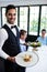Portrait of waiter standing with meal next to customers
