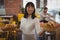 Portrait of waitress holding baskets with sandwiches while businessman using laptop