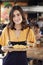 Portrait Of Waitress Serving Food To Customers In Busy Bar Restaurant