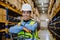 Portrait of warehouse female worker in reflective vest with a pallet truck.