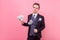 Portrait of wealthy rich man holding money and looking arrogant successful. indoor studio shot isolated on pink background