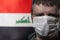 Portrait of a white man in a medical mask on the background of the flag of Iraq