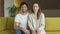 Portrait of a wife and husband waving their hands looking at the camera saying hello sitting on the sofa in the living