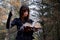 Portrait of a witch with an open magic book of spells on the background of an autumn forest. Beautiful young woman in black