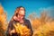 Portrait of a woman in the autumn sun looks up. Girl holding a bouquet of autumn leaves at sunset