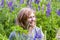 Portrait of a woman on a background of blooming lupines. Relaxed, natural emotions and look