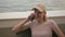 Portrait of a woman in a baseball cap talking on the phone, sitting on the balcony of a hotel room overlooking the sea.