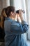 Portrait of woman with binoculars looking out the window, spying on neighbors, side view