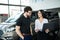 Portrait of a woman car seller and her potential buyer looking at laptop in the showroom