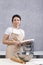 Portrait of woman chef in kitchen with cookbook in her hands. Bowl and rolling pin on table. Vertical frame