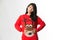 Portrait of woman in Christmas sweatershowing she has eaten too much food over gray background