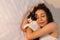 Portrait of woman with curly hair sleeping with her black and white cat in bed. Concept of love to animals, pets, care,