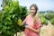 Portrait of woman cutting grapes through pruning shears at vineyard