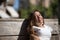 Portrait of woman with disability, reduced mobility and small stature sitting on a wooden bench, happy and relaxed sunbathing.