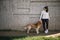 Portrait of woman and dog standing in front of stone wall