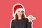 Portrait of woman in dress pointing left with thumb and confused. emotional girl in santa claus christmas hat isolated on white