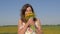 Portrait of woman in field with bouquet of yellow dandelion flowers sniffing him