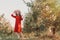 Portrait of a woman in the garden. A young and beautiful woman in a red dress and hat coquettishly takes off her hat. Copy space