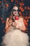 Portrait of woman with ghost make-up and wedding dress holding abstract bloody apple