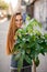 portrait of woman in glasses with long hair holding pachira plant in her hands