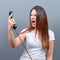 Portrait of woman having unpleasant phone call against gray background