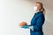 Portrait of woman holding plates of Italian pasta wearing protective surgical mask and latex gloves