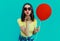 Portrait woman with lollipop and red balloon blowing a red lips on a blue background