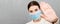 Portrait of a woman in medical mask with Stay home text and showing stop gesture at gray cement background. Coronavirus self