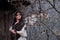 Portrait of a woman near the wall of an old house with tree branches. Girl in vintage clothes, gloomy photo for Halloween, copy