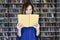 Portrait of woman over 25 in a library covered by opened book, long hair. Young college student in co-working, concept of studying