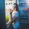 Portrait of woman in pajamas eating pizza at open fridge at nigh